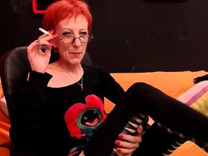 Une rousse chaude avec des lunettes savoure une cigarette et perd