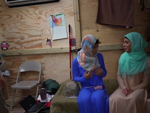 Deux nanas arabes s'embrassent pendant que des soldats regardent. Deux