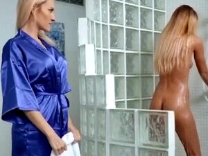Une MILF blonde et une mignonne s'amusent ensemble sous la douche. La