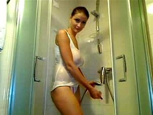 Une beauté naturelle prend une douche avec une chemise blanche